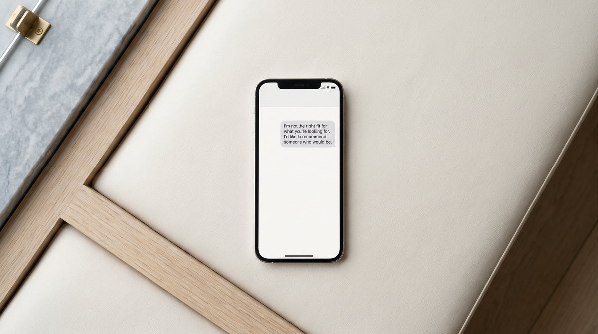 A phone on a salon counter showing a single sent text message that reads: I'm not the right fit for what you're looking for. I'd like to recommend someone who would be.